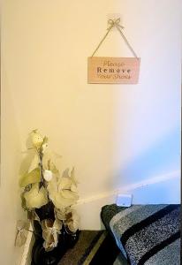 a sign hanging on a wall with a plant at Cozy single room in city center in Newry
