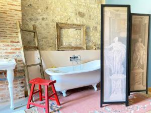 a bathroom with a white tub and a red stool at Gorgeous old house in the centre of Souillac in Souillac