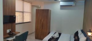 a hotel room with a bed and a wooden cabinet at Hotel The Marion in Nashik