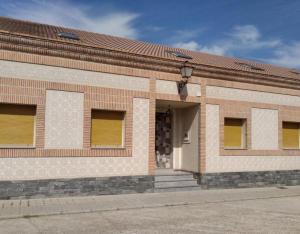 a brick building with yellow doors and a porch at El Nogal De Nieva in Nieva