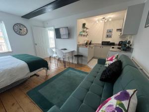 a living room with a green couch and a kitchen at The Boardroom in Hathern