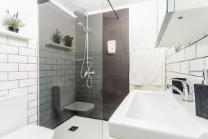 La salle de bains blanche est pourvue d'un lavabo et d'une douche. dans l'établissement Apartamento Daniella, à Puerto Naos