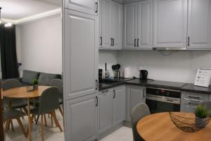 a kitchen with white cabinets and a table and a dining room at Apartament Argento in Toruń