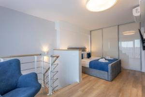 een slaapkamer met een bed en een blauwe stoel bij Ferienwohnung am Meer, Urlaub auf der Insel Usedom, Apartment Albus 409 in Świnoujście