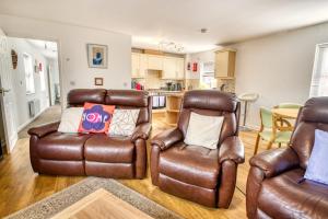 a living room with two leather chairs and a kitchen at Pass the Keys Well equipped apartment near A46 in Swinderby