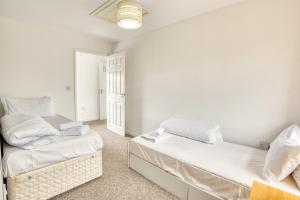 two beds in a room with white walls at Pass the Keys Well equipped apartment near A46 in Swinderby