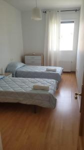 three beds in a room with a window and wooden floors at Apartamento Cattleya in Almazán