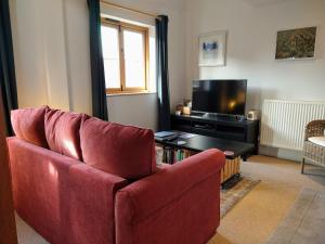 a living room with a red couch and a television at The Studio, Upper House Farm, Crickhowell with Double Garage and Free Parking in Crickhowell