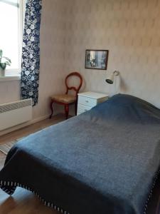 a bedroom with a bed and a chair and a window at Täljelantgårdshotell in Tälje