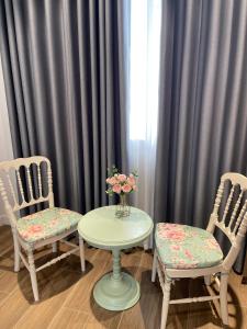 two chairs and a table with a vase of flowers at Lucia Villa - Melorita Hòa Lạc in Hanoi