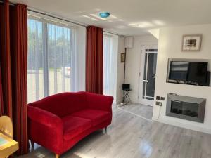 a living room with a red chair and a television at Sutton Coach House in Wexford