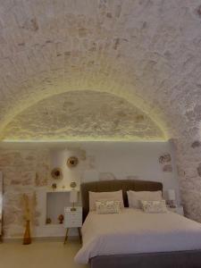 1 dormitorio con 1 cama con pared de piedra en Eureka luxury room, en Ostuni