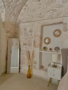 Habitación con pared de piedra, jarrón y espejo. en Eureka luxury room, en Ostuni