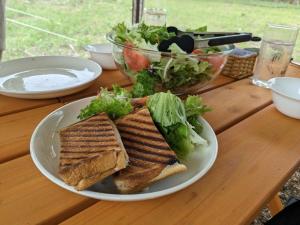 Mimasaka的住宿－Glamchette Okayama -Glamping & Auto Camp- - Vacation STAY 19606v，木桌上盘子里的三明治和沙拉