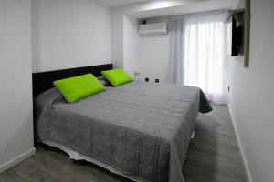 um quarto com uma cama com almofadas verdes e uma janela em Quijano Hotel - Aparts & Suites em Montevidéu