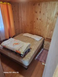 a small bed in a room with wood paneling at Cabañas Las Olas in Constitución