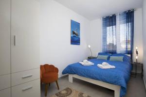 een slaapkamer met een blauw bed en handdoeken bij Villa Kostre in Loborika