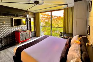 Un dormitorio con una cama grande y una ventana grande. en Hotel Helene, en Medellín