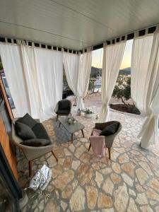 una sala de estar con cortinas y sillas blancas y una mesa. en Tolles Ferienhaus in Kornati mit Whirlpool, Terrasse und gemeinschaftlichem Pool, en Pristanišće