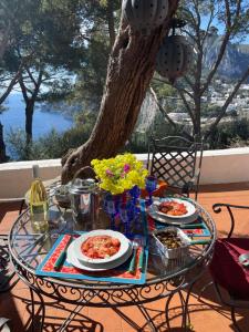 een patio tafel met borden met eten erop bij Villa Guya in Capri