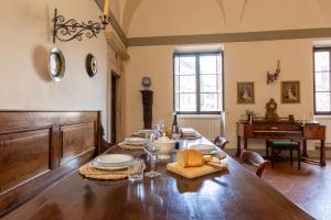 uma sala de jantar com uma mesa longa e um piano em Palazzo Costanti - A 8 minuti dalle terme em San Quirico dʼOrcia