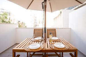 een houten tafel met 2 stoelen en een parasol bij Brand New 2 Bed 2 Bath Apartment In Sliema By The Sea in Sliema
