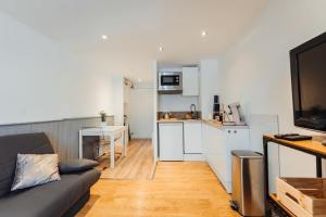 uma sala de estar com um sofá e uma cozinha em Punta Helbronner Furnished studio em Saint-Gervais-les-Bains