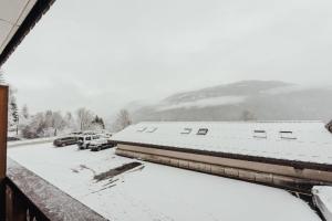 a snow covered building with cars parked in a parking lot at Punta Helbronner Furnished studio in Saint-Gervais-les-Bains