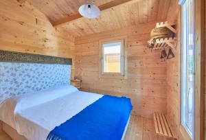 ein Schlafzimmer mit einem Bett in einer Holzhütte in der Unterkunft Lakeside Cabin Oasis w/ AC, By TimeCooler in Montargil