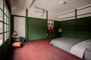ein Schlafzimmer mit grünen Wänden und einem Bett darin in der Unterkunft Xinghua Room in Kaohsiung
