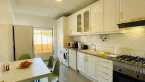 a kitchen with white cabinets and a table with a bowl of fruit at Bicos 303 - Shared Pool - 6 Guests - Albufeira in Albufeira