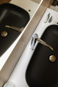 two black sinks in a kitchen with a fosset at Ginevra Boutique Rooms - Palazzo Leosini - Residenze D'Epoca in LʼAquila