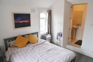 Un dormitorio con una cama con almohadas amarillas y una ventana. en Castle Manor, 4 Bed Seaside Retreat, en Scarborough