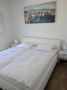 een wit bed met een foto aan de muur bij Ferienwohnung in Nin mit Großer Terrasse in Nin