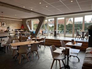 een restaurant met tafels, stoelen en ramen bij Villavelo Twente in Ootmarsum