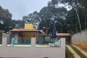 Casa com piscina Embu-Guaçu/ Itapecerica (Chácara) في Embu-Guaçu: منزل فيه مظله وطاولة وكراسي