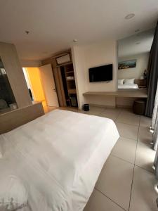 a bedroom with a white bed and a flat screen tv at Villa biển Oceanami B805 - Ô tô đậu trước cửa nhà in Long Hai