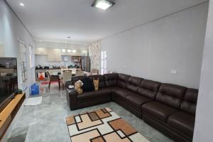 ein Wohnzimmer mit einem braunen Sofa und einer Küche in der Unterkunft Casa com piscina Embu-Guaçu/ Itapecerica (Chácara) in Embu-Guaçu