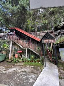 una casa con balcón y una señal frente a ella en Hillside cottage tanah rata, en Tanah Rata