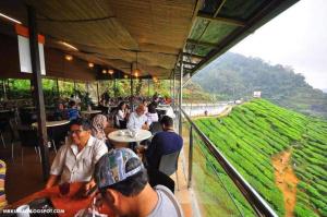 un groupe de personnes assises à table dans un restaurant dans l'établissement Hillside cottage tanah rata, à Tanah Rata