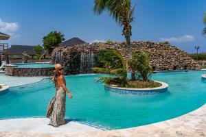 Una mujer parada frente a una piscina con cascada. en Bed & Bike Westpunt, en Westpunt
