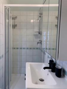 a white bathroom with a sink and a shower at Lotus - Designer apt in city center in Zagreb