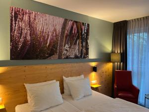 a hotel room with a bed and a red chair at Villavelo Twente in Ootmarsum