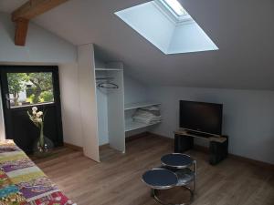 a bedroom with a skylight and two stools and a television at L'atelier de Jean in Velzic