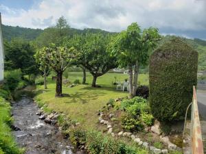 a garden with trees and a stream with a table and chairs at L'atelier de Jean in Velzic