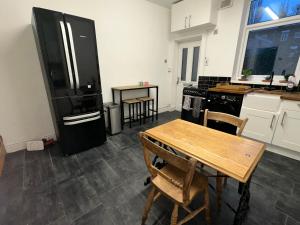 eine Küche mit einem Holztisch und einem schwarzen Kühlschrank in der Unterkunft Commuters Getaway in Chesterfield