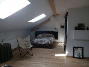 a bedroom with a bed and a chair in a attic at L'atelier de Jean in Velzic