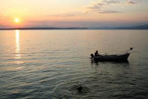 Ein Mann in einem Boot im Wasser bei Sonnenuntergang. in der Unterkunft Studio für 5 Personen ca 48 qm in Šilo, Kvarner Bucht Krk in Šilo