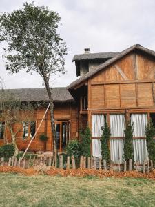 ein Holzhaus mit einem Baum davor in der Unterkunft Wooden House - Melorita Hòa Lạc in Hanoi