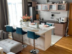 uma cozinha com uma ilha branca com cadeiras azuis em Kunderi apartment with sauna em Rakvere
